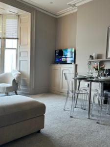 a living room with a table and chairs and a television at Lan Y Môr 4 Aberystwyth in Aberystwyth