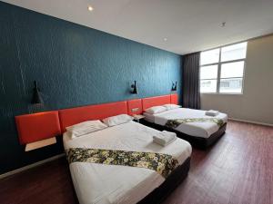 um quarto de hotel com duas camas e uma parede azul em Win Win Boutique Hotel PD em Port Dickson