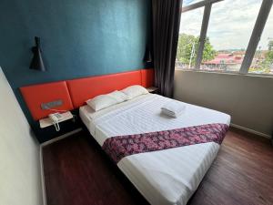 a bedroom with a bed with an orange headboard and a window at Win Win Boutique Hotel PD in Port Dickson
