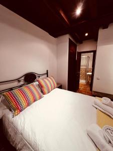 um quarto com uma grande cama branca com almofadas coloridas em Rascacielos San Martín em Cuenca