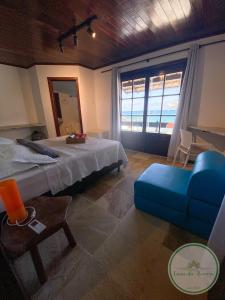 um quarto com uma cama grande e uma cadeira azul em Casa da Barra em Barra de São Miguel