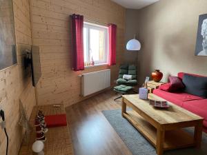 uma sala de estar com um sofá vermelho e uma mesa em Aparthotels Berwang / Haus Wiesengrund em Berwang