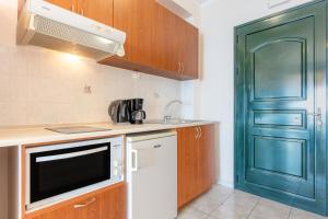 a kitchen with a sink and a microwave and a door at Lido Sofia Apartments in Agios Gordios
