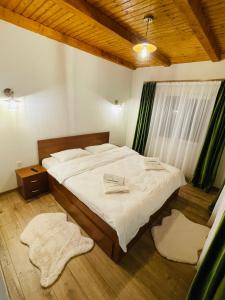 een slaapkamer met een bed met witte lakens en een raam bij Casa Ceteras in Cavnic