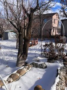 un patio cubierto de nieve con un árbol y un banco en Vacantion home - Modern design with beautiful view en Aparan