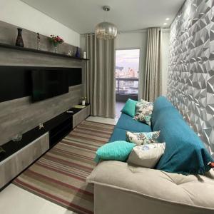 Una sala de estar con un sofá y un televisor de pantalla plana. en Apartamento no Boqueirão, Perto Praia com Piscina, en Praia Grande