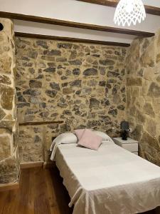 Cama en habitación con pared de piedra en Apartamento Rural Piedra, en Jérica