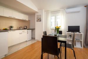 a kitchen with a table and chairs and a kitchen with white cabinets at Apartments Luka free bikes in Rovinj