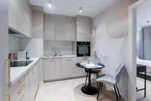 a kitchen with white cabinets and a small table at Grzybowska Rooms by Sofija in Warsaw