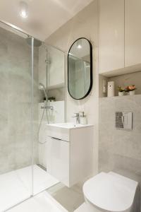 uma casa de banho branca com um lavatório e um chuveiro em Grzybowska Rooms by Sofija em Varsóvia