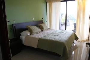 ein Schlafzimmer mit einem Bett und einem großen Fenster in der Unterkunft Casa Mon Coeur-Playa Del Coco Ocean View in Coco
