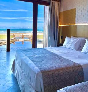a bedroom with two beds and a view of the beach at Resort Tororomba in Olivença