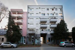 a white building with cars parked in front of it at Apartment Queen - private parking in Osijek