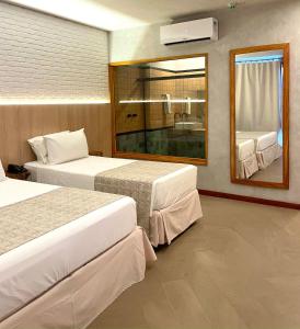 a hotel room with two beds and a mirror at Resort Tororomba in Olivença