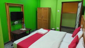 a green room with a bed and a television at SM Residency in Coimbatore +4 photos