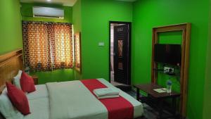 a green bedroom with a bed and a television at SM Residency in Coimbatore