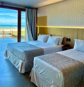 two beds in a hotel room with a view of the ocean at Resort Tororomba in Olivença