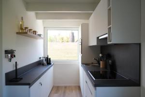 cocina con armarios blancos, fregadero y ventana en Stormvloed en Renesse