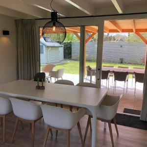 uma sala de jantar com uma mesa branca e cadeiras em Stormvloed em Renesse