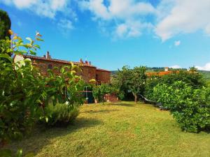 芬奇的住宿－Poderino La Noce，一座老砖砌的建筑,在院子里有树木和灌木