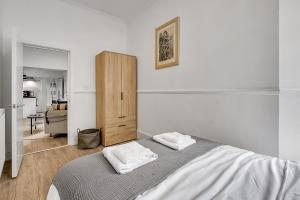 a white bedroom with a bed and a wooden cabinet at Lovely Kensington Apartments in London