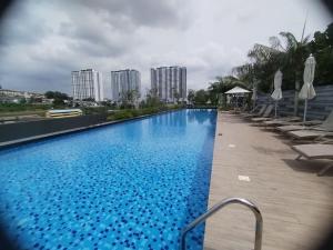 a large blue swimming pool with chairs and buildings at Japandi Family Play Suite with Slide Bunk Bed in Kajang
