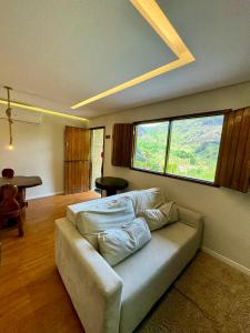 a living room with a couch and a large window at EcoFlat Moderno e Aconchegante in Bonito