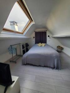a bedroom with a bed in a attic with a window at Charmante maison, 40mn de Paris in Triel-sur-Seine