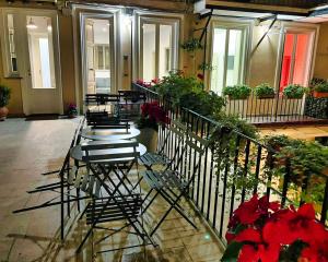 ローマにあるWhite Style Gamberoの花の咲くバルコニーにテーブルと椅子が並ぶ