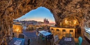 een restaurant in een grot met tafels en stoelen bij Pergola Hotel & Spa in Mellieħa