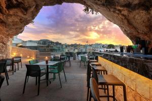 a restaurant with tables and chairs and a view of a city at Pergola Hotel & Spa in Mellieħa