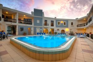 a pool in the middle of a building with a patio at Pergola Hotel & Spa in Mellieħa
