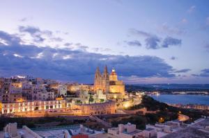 a view of a city at night at Pergola Hotel & Spa in Mellieħa