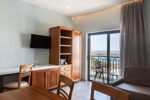 a living room with a desk and a balcony at Pergola Hotel & Spa in Mellieħa