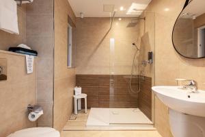 a bathroom with a shower and a toilet and a sink at Pergola Hotel & Spa in Mellieħa