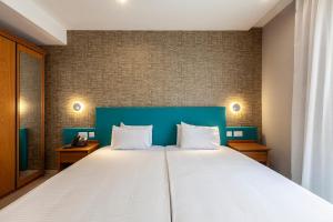 a bedroom with a large bed with a blue headboard at Pergola Hotel & Spa in Mellieħa