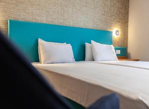 a large bed with a blue headboard and white pillows at Pergola Hotel & Spa in Mellieħa