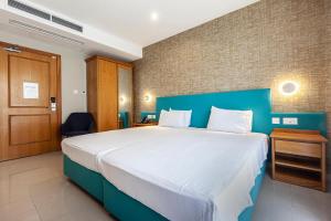 a bedroom with a large bed with a blue wall at Pergola Hotel & Spa in Mellieħa