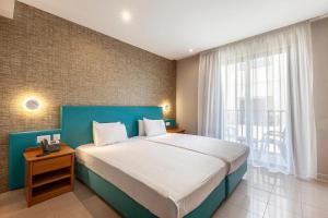 a bedroom with a large bed and a large window at Pergola Hotel & Spa in Mellieħa