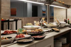 a buffet with bowls and plates of food on a table at Pergola Hotel & Spa in Mellieħa