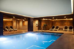 a large swimming pool in a hotel with chairs at Pergola Hotel & Spa in Mellieħa