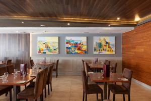 a restaurant with wooden tables and chairs and paintings on the wall at Pergola Hotel & Spa in Mellieħa