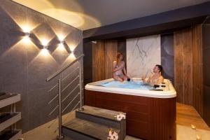 two women sitting in a tub in a bathroom at Pergola Hotel & Spa in Mellieħa