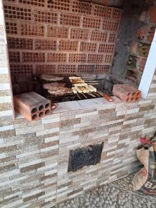 una pared de ladrillo con una parrilla con comida. en Pousada dos Pinheiros, en Guaraqueçaba