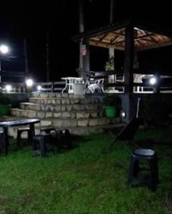 un patio nocturno con mesa y sillas en Pousada dos Pinheiros, en Guaraqueçaba