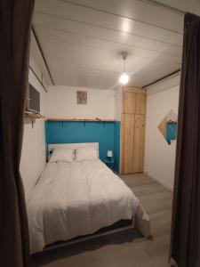 a bedroom with a bed with a blue headboard at Residence l'Oncet - Appartement 8 personnes in Barèges +2 photos
