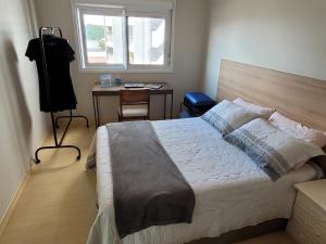 Schlafzimmer mit einem Bett, einem Schreibtisch und einem Fenster in der Unterkunft Nosso Ap em Bento in Bento Gonçalves