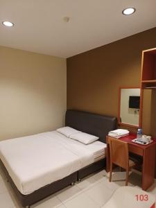 a bedroom with a bed and a desk with a mirror at Doris Hotel in Melaka