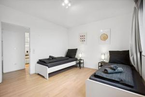 two beds in a room with white walls and wooden floors at OH05 Apartment in Flughafennähe! in Mörfelden-Walldorf