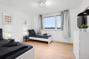 a white living room with a couch and a window at OH05 Apartment in Flughafennähe! in Mörfelden-Walldorf